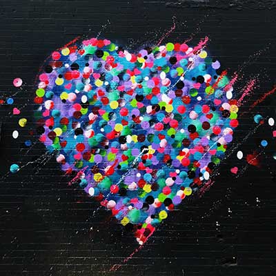 Colourful dots in a heart shape on black background