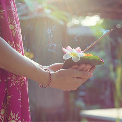 A woman's hand holding daily offerings in Bali